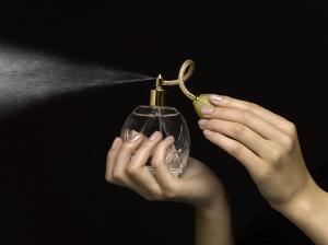 Woman spraying perfume with perfume atomizer, close-up of hands